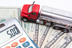 Image of calculator, money, and a small long haul truck